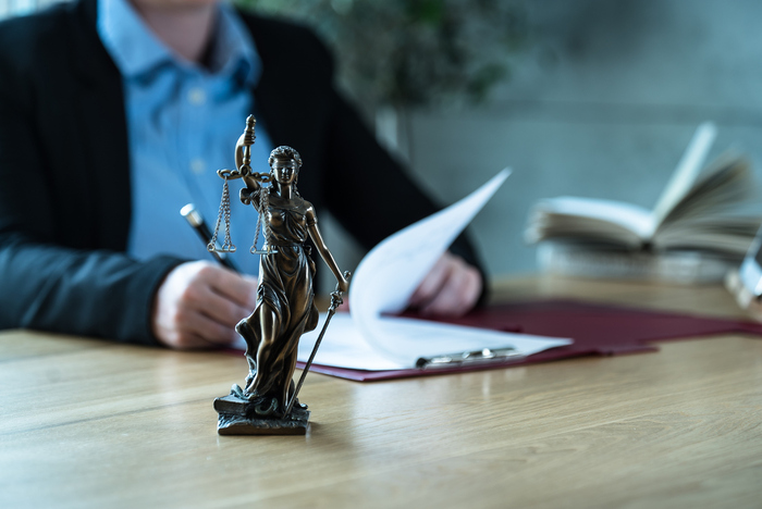 Lawyer office. Statue of Justice with scales and lawyer working on papers, Advice and justice concept.